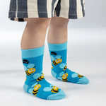 Child wearing blue socks with bee designs on a white background