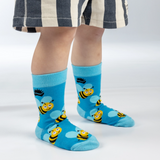Child wearing blue socks with bee designs on a white background