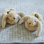 Pair of beige bunny slippers on a textured surface