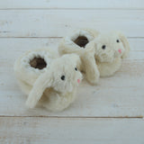 Pair of fluffy bunny slippers on a wooden surface
