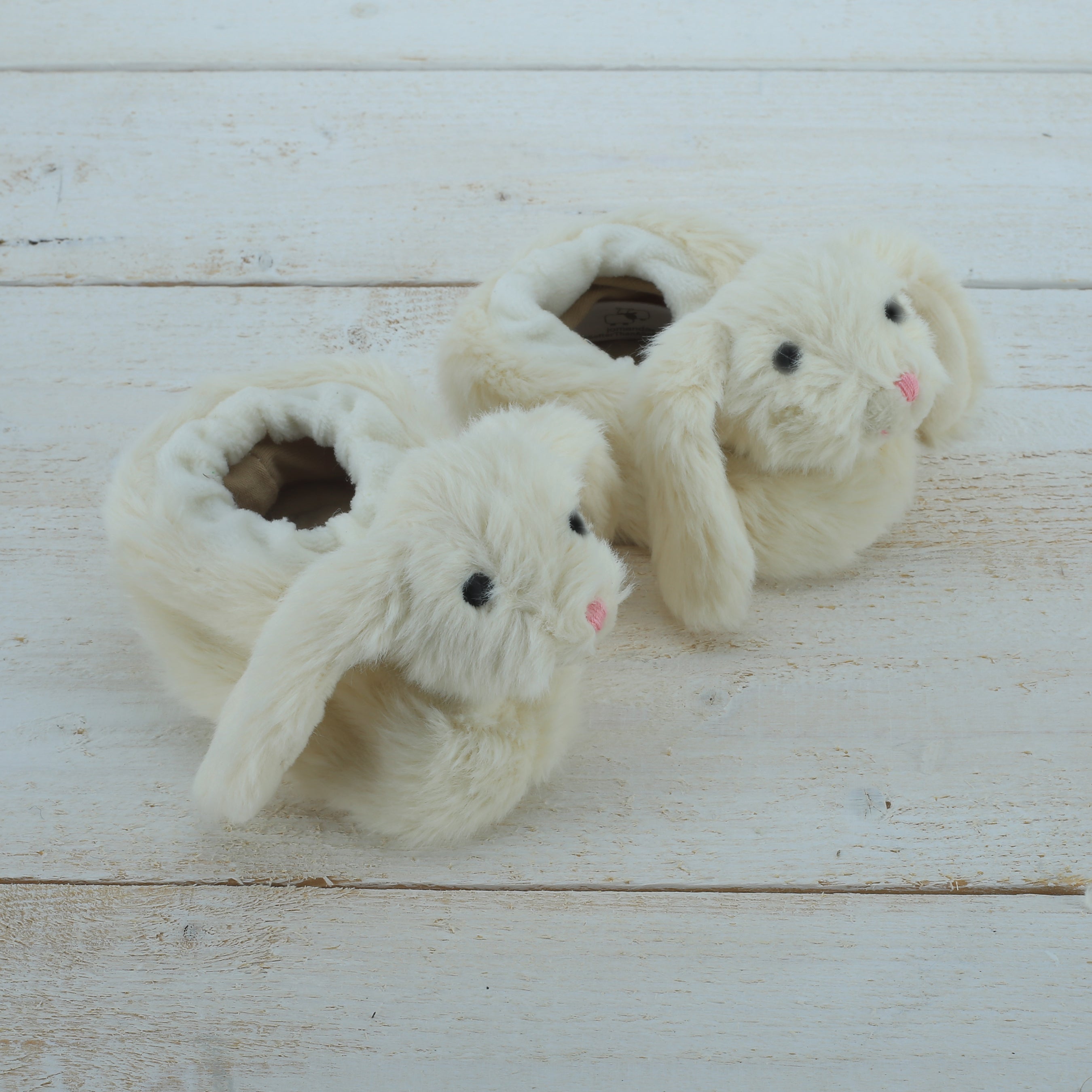 Pair of fluffy bunny slippers on a wooden surface