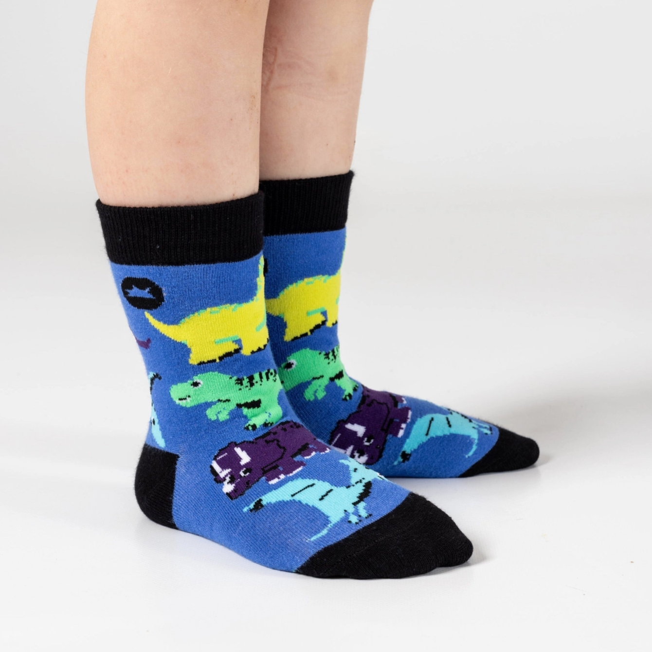 Blue socks with dinosaur design worn by a person on a white background