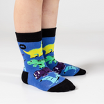 Blue socks with dinosaur design worn by a person on a white background
