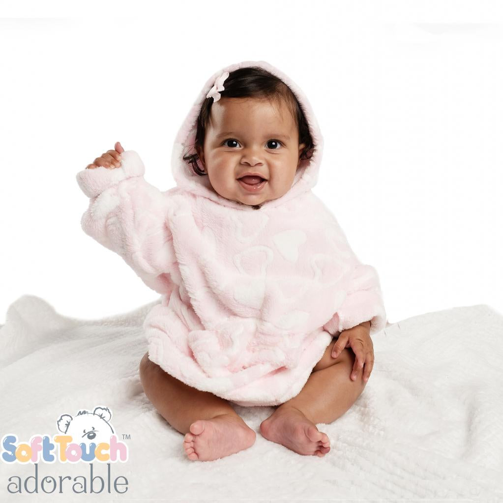 A baby wearing a pink hooded jacket with a heart pattern, sitting on a white blanket.