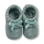 A pair of sage green baby booties with a cute bow detail.