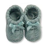 A pair of sage green baby booties with a cute bow detail.