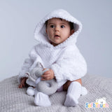 A baby wearing a white waffle hoodie with a hood pocket, paired with white pants, sitting and holding a gray toy.